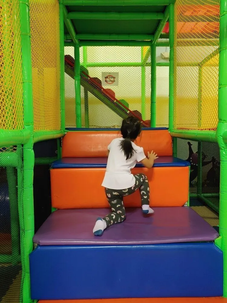 Child climbing toward the indoor slide area at DinoDash