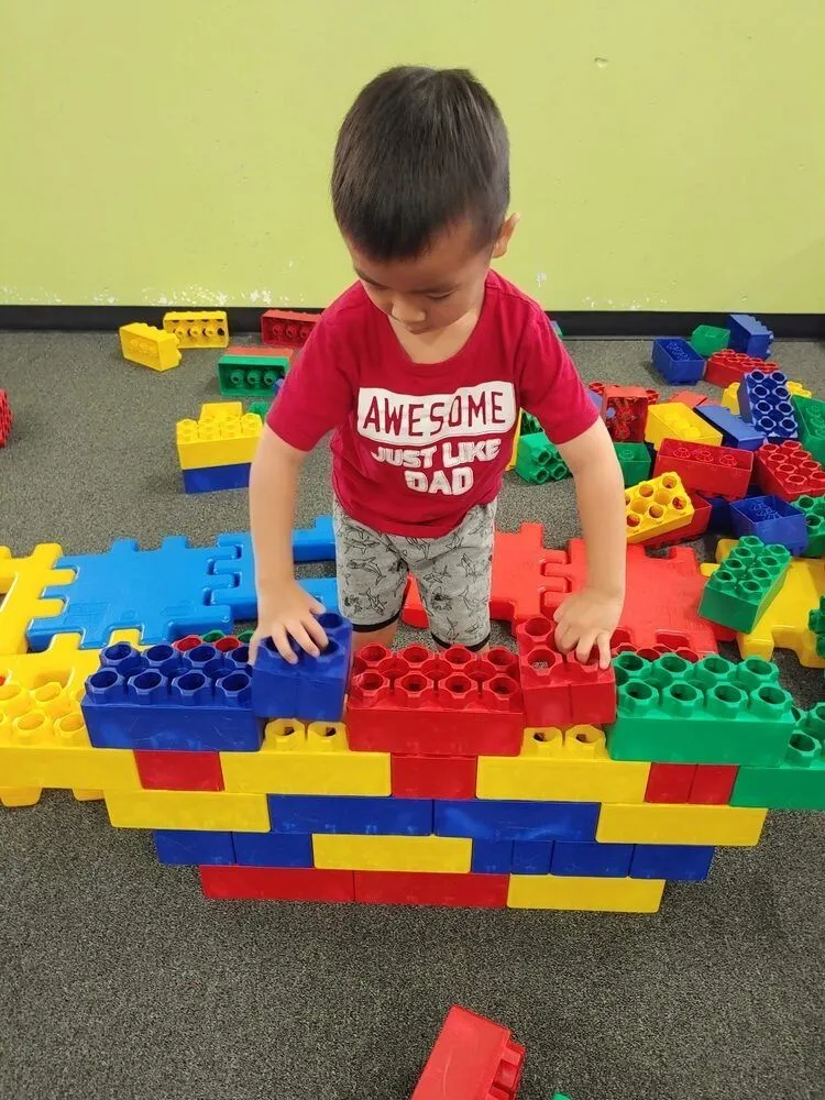 Child building with large colorful Lego-style blocks at DinoDash
