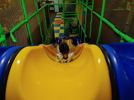 Child sliding down an indoor yellow slide at DinoDash